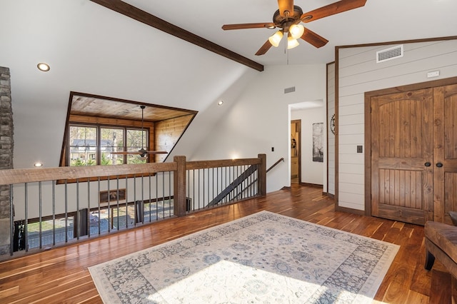 entrance foyer with ceiling fan, dark hardwood / wood-style flooring, beamed ceiling, high vaulted ceiling, and wood walls