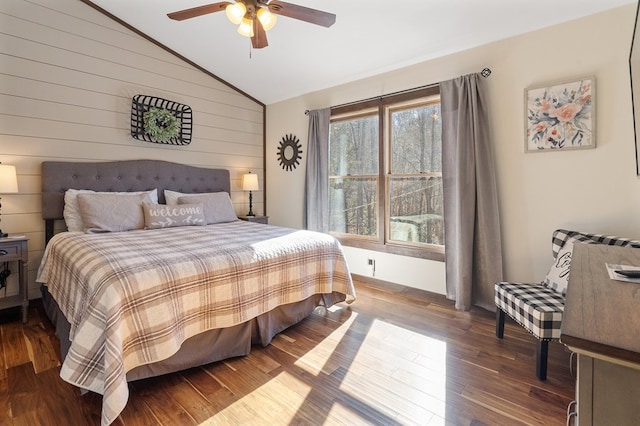 bedroom with wood-type flooring, lofted ceiling, ceiling fan, and wooden walls