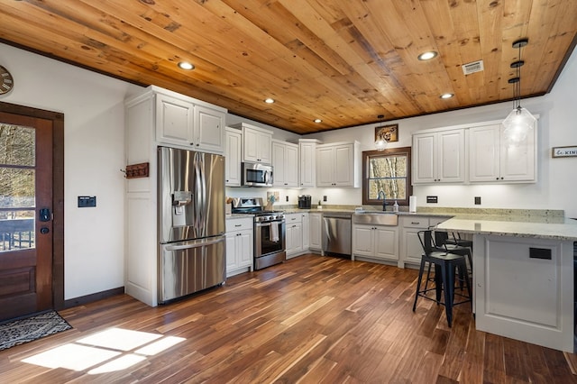 kitchen featuring stainless steel appliances, white cabinetry, hanging light fixtures, and a healthy amount of sunlight