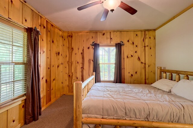 carpeted bedroom with wood walls and ceiling fan