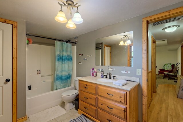 full bathroom featuring a notable chandelier, vanity, shower / bathtub combination with curtain, toilet, and tile patterned flooring