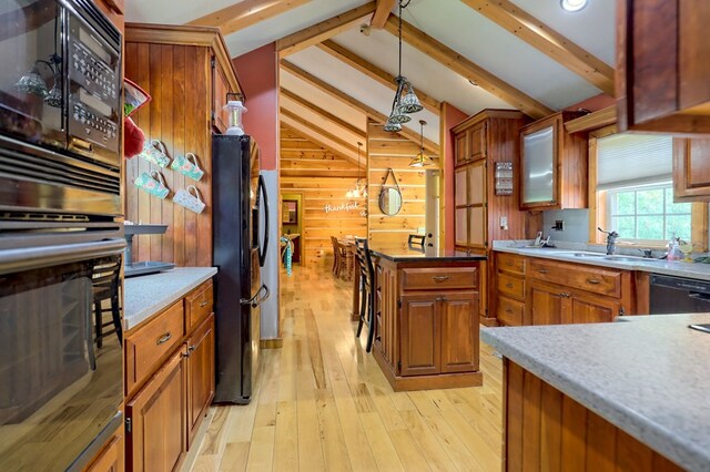 kitchen with vaulted ceiling with beams, wood walls, light hardwood / wood-style floors, black appliances, and pendant lighting