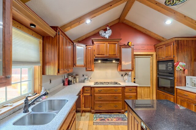 kitchen featuring black appliances, light hardwood / wood-style flooring, sink, and vaulted ceiling with beams