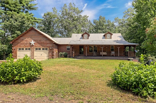 log-style house with covered porch, a garage, and a front yard