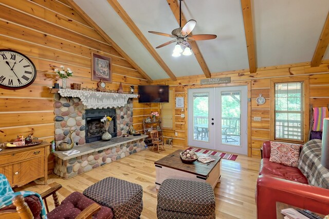 living room featuring vaulted ceiling with beams, a fireplace, french doors, ceiling fan, and wood-type flooring