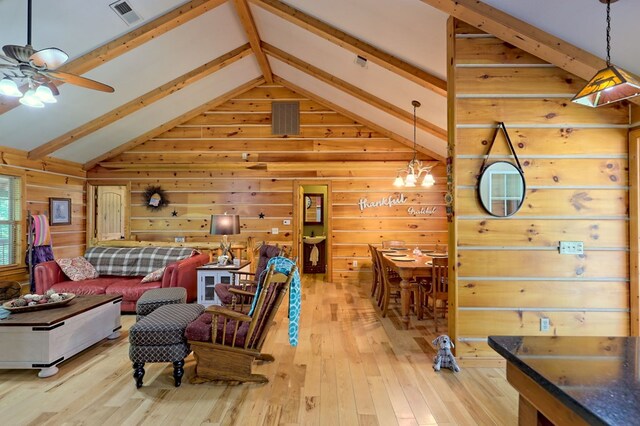 living room with lofted ceiling with beams, wooden walls, and light hardwood / wood-style flooring