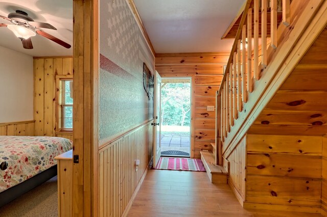 bedroom featuring wood-type flooring, wooden walls, and ceiling fan