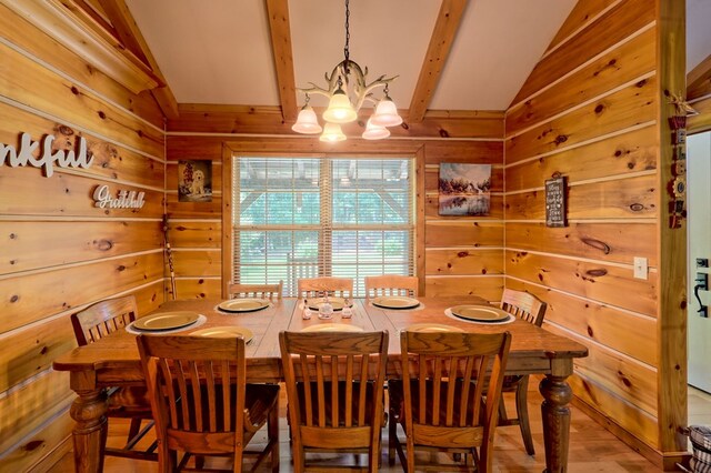 dining space with vaulted ceiling with beams, a chandelier, wooden walls, and hardwood / wood-style floors