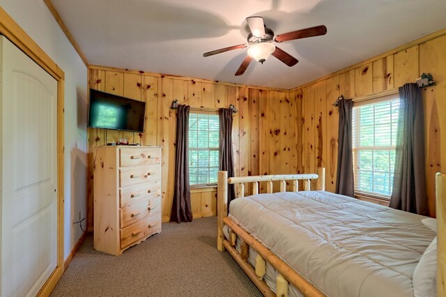 bedroom featuring ceiling fan, wooden walls, a closet, and light colored carpet