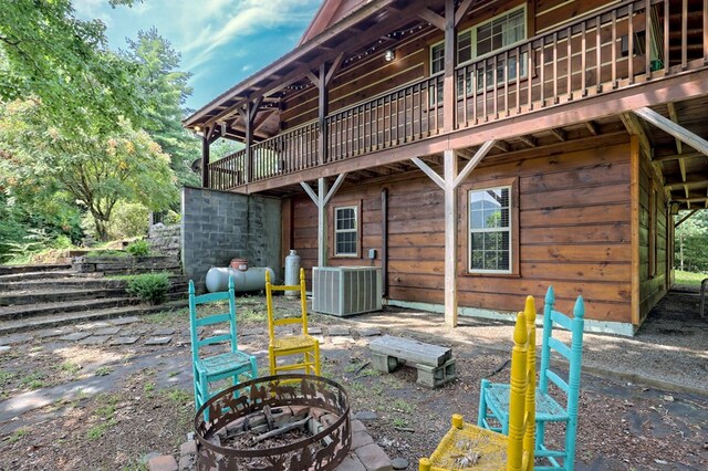 back of property with central AC unit and an outdoor fire pit