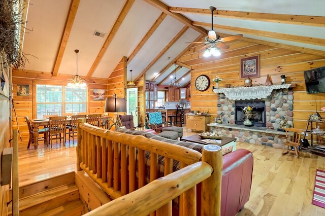 living room featuring a fireplace, light hardwood / wood-style floors, ceiling fan with notable chandelier, beam ceiling, and wood walls