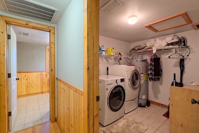 laundry area featuring separate washer and dryer, water heater, and light tile patterned floors