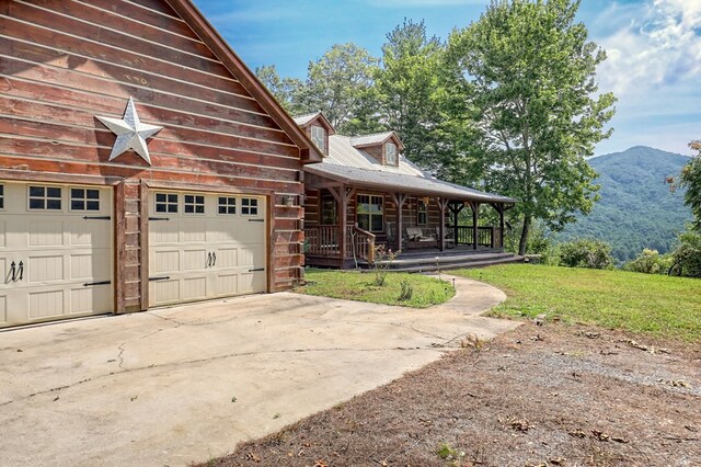 exterior space featuring a garage, covered porch, a mountain view, and a front yard