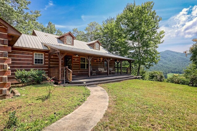 cabin with a mountain view, a front yard, and covered porch