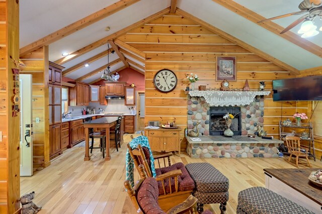 living room with a fireplace, ceiling fan, sink, lofted ceiling with beams, and light hardwood / wood-style floors