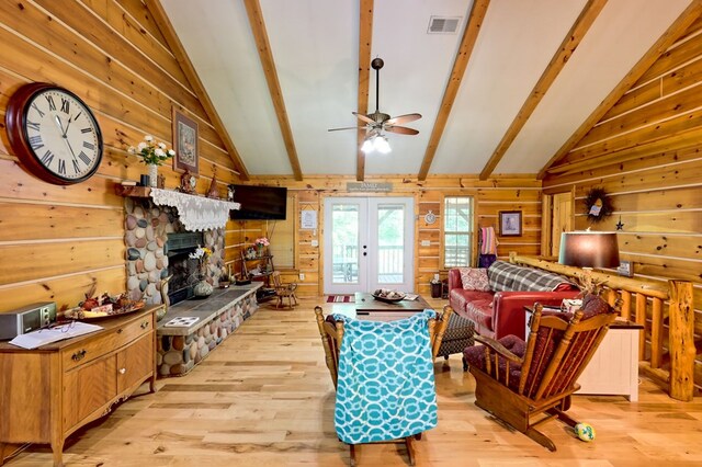 living room featuring vaulted ceiling with beams, a fireplace, french doors, light wood-type flooring, and ceiling fan