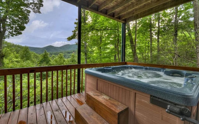 wooden terrace with a mountain view, a wooded view, and a hot tub