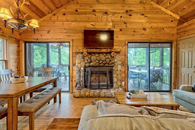 living room with hardwood / wood-style floors, wood ceiling, wood walls, and a stone fireplace