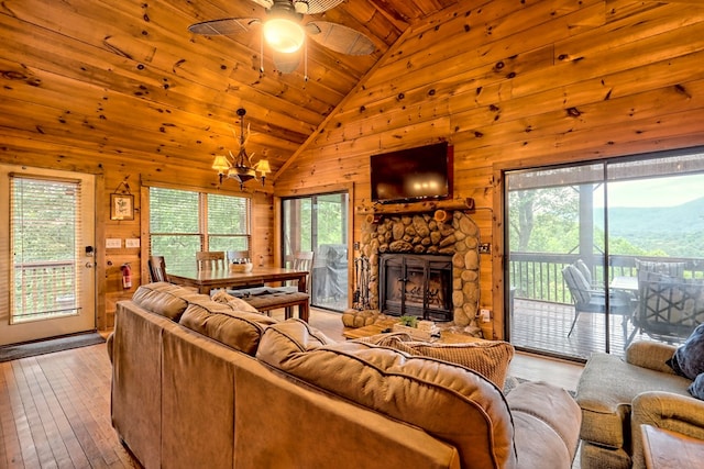 living area featuring high vaulted ceiling, a fireplace, wood-type flooring, wood walls, and wooden ceiling