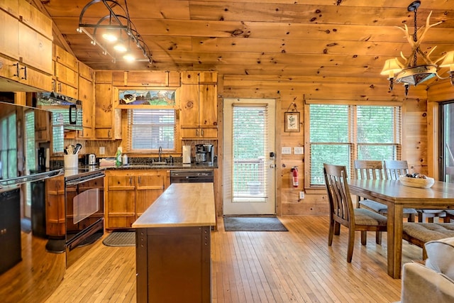 kitchen featuring light wood finished floors, wood walls, wooden counters, and brown cabinetry