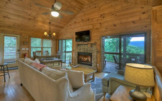 living area with high vaulted ceiling, wood-type flooring, wooden walls, wooden ceiling, and a fireplace