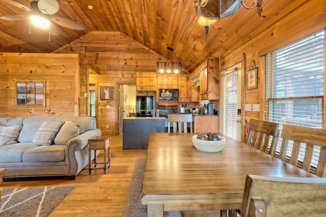 dining area featuring light wood-style flooring, a ceiling fan, wood walls, wooden ceiling, and vaulted ceiling