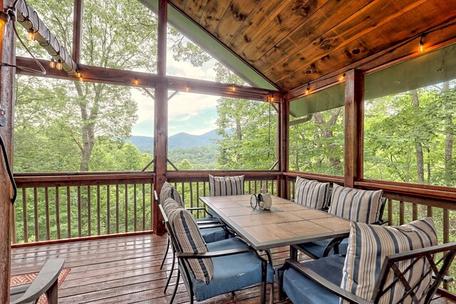 wooden deck with outdoor dining space and a mountain view