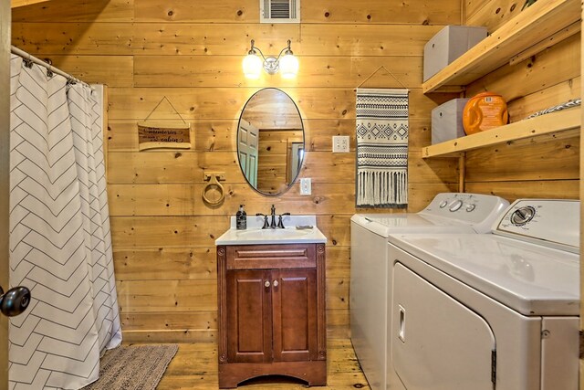 laundry area featuring wooden walls, visible vents, laundry area, a sink, and independent washer and dryer