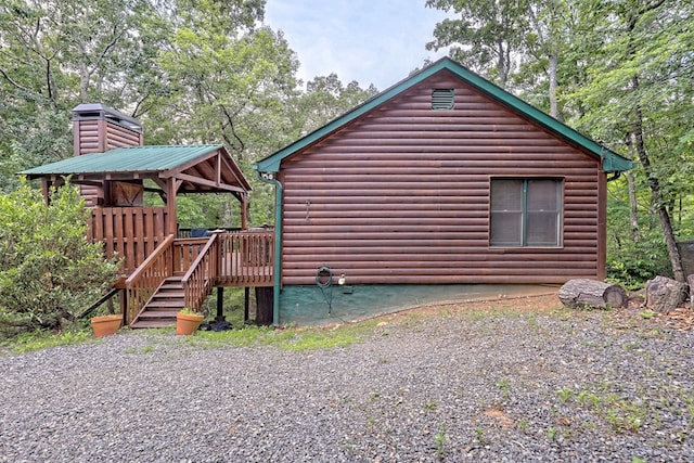 view of home's exterior featuring faux log siding, a chimney, and a deck