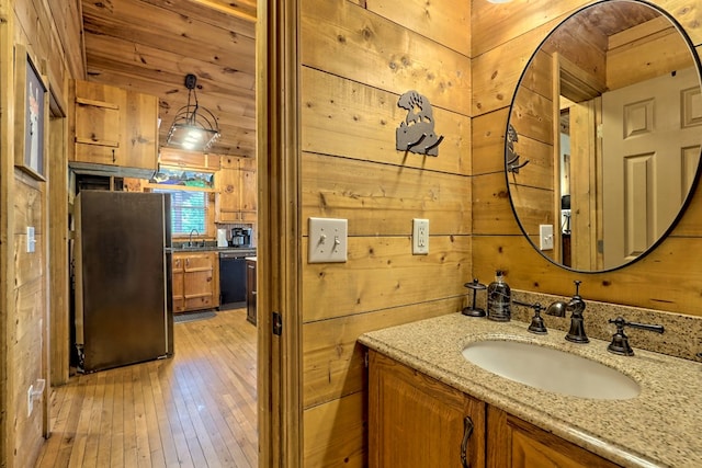 bathroom with wooden walls, vanity, and hardwood / wood-style floors