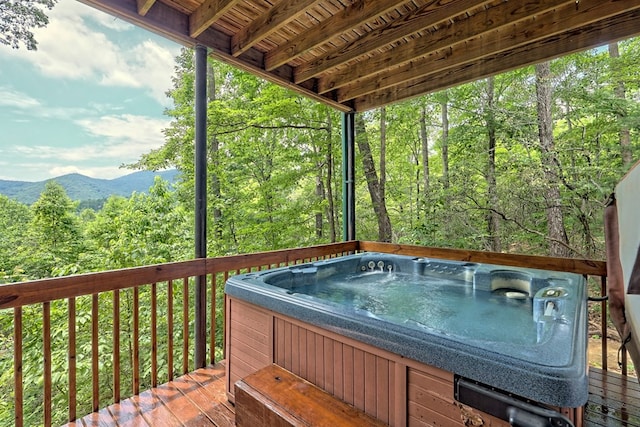 deck with a forest view and a hot tub