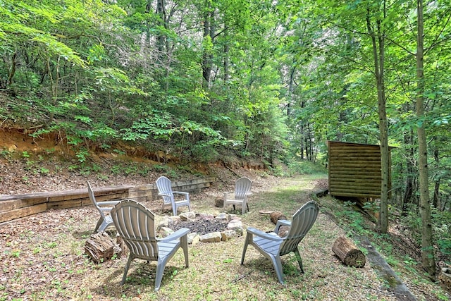 view of yard featuring a wooded view and an outdoor fire pit