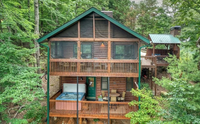 back of house with metal roof, a chimney, and a sunroom