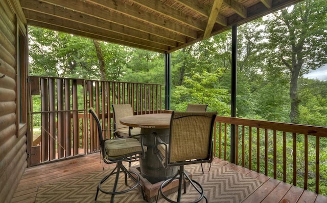 wooden deck with a wooded view and outdoor dining area