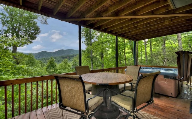 wooden terrace with outdoor dining area, a wooded view, and a mountain view