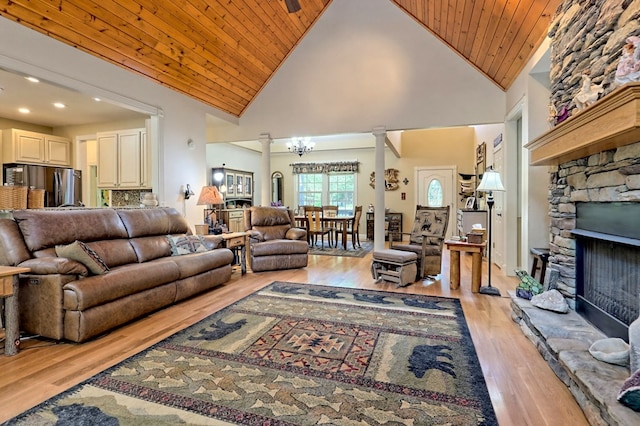 living room featuring wooden ceiling, light hardwood / wood-style flooring, high vaulted ceiling, a notable chandelier, and a fireplace