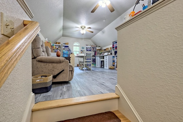 living room featuring a textured ceiling, ceiling fan, hardwood / wood-style floors, and vaulted ceiling