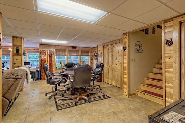 dining space with a paneled ceiling and wood walls