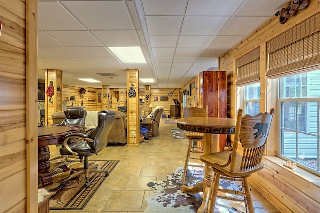 interior space featuring a paneled ceiling and wooden walls