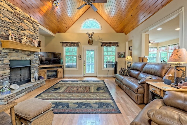 living room featuring a wealth of natural light, a fireplace, wooden ceiling, and light wood-type flooring