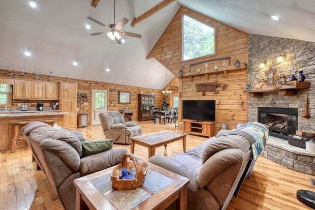 living room with high vaulted ceiling, wood walls, light hardwood / wood-style floors, and plenty of natural light