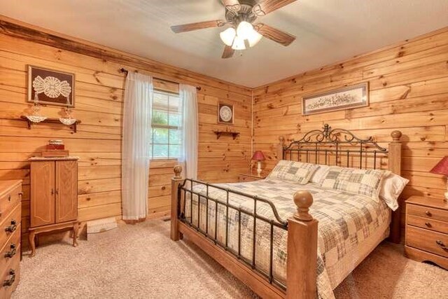 bedroom featuring light colored carpet, wooden walls, and ceiling fan