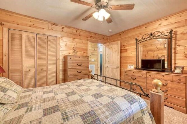 bedroom with a closet, ceiling fan, and wooden walls