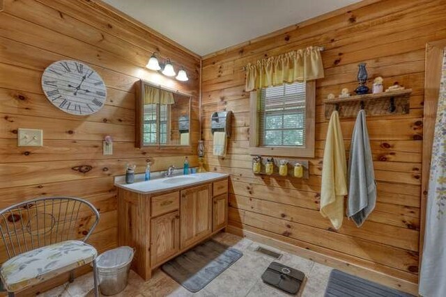 bathroom with wood walls, vanity, and tile patterned floors