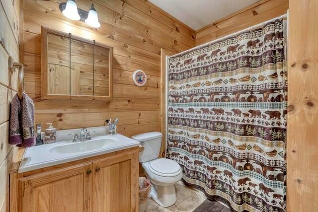 bathroom featuring toilet, wooden walls, vanity, and tile patterned floors