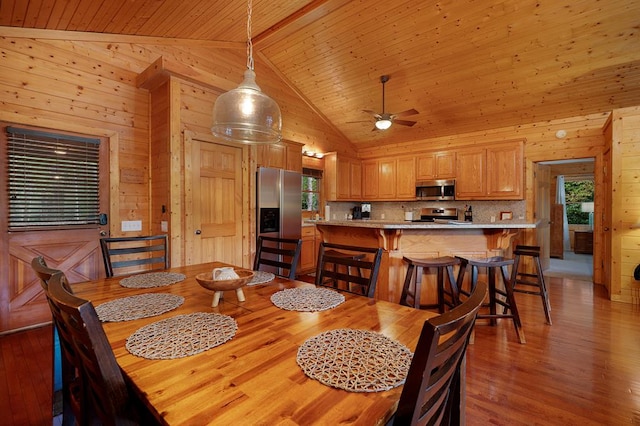 dining area with wooden walls, light wood-type flooring, high vaulted ceiling, and wooden ceiling