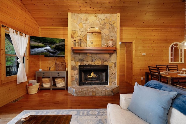 living room with wood walls, a fireplace, vaulted ceiling, and hardwood / wood-style flooring