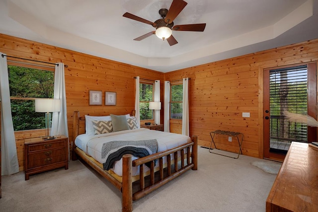 carpeted bedroom featuring access to outside, wood walls, and ceiling fan