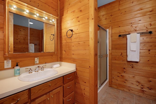 bathroom with vanity, a shower with shower door, wood walls, and tile patterned floors