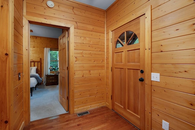 doorway with wooden walls and light wood-type flooring